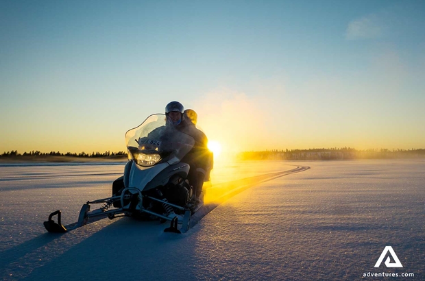 driving snowmobile by the sunset in Sweden
