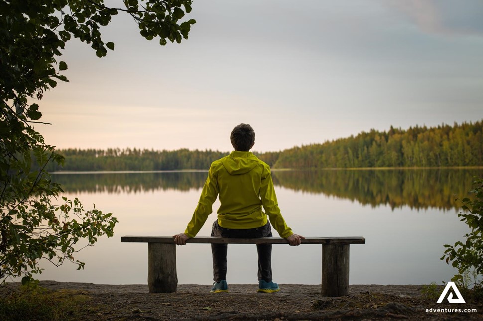 man sitting on a bench in finland and enjoying landscape