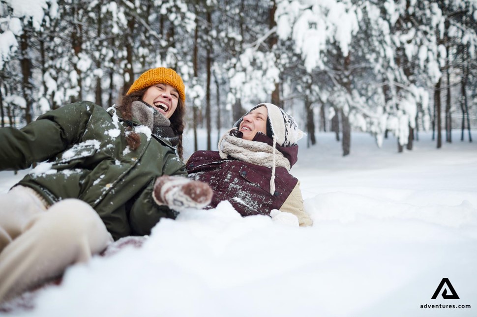 happy couple laying in the snow in finland