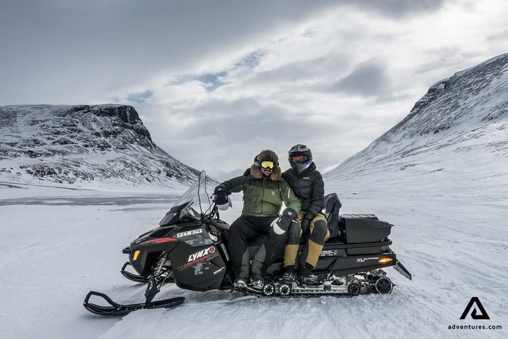 friends sitting on snowmobile