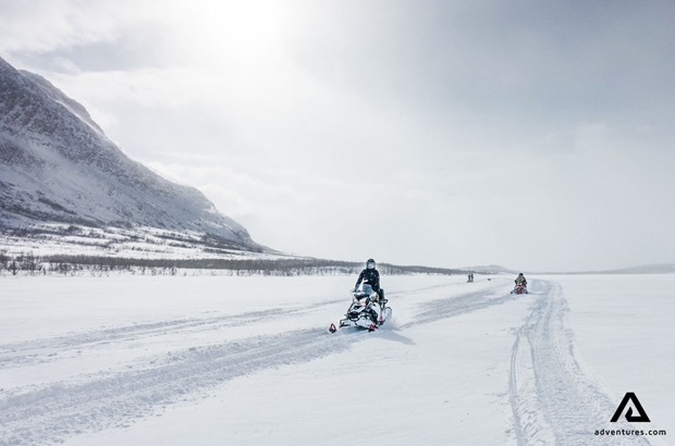 Small group driving snowmobiles in snowy field
