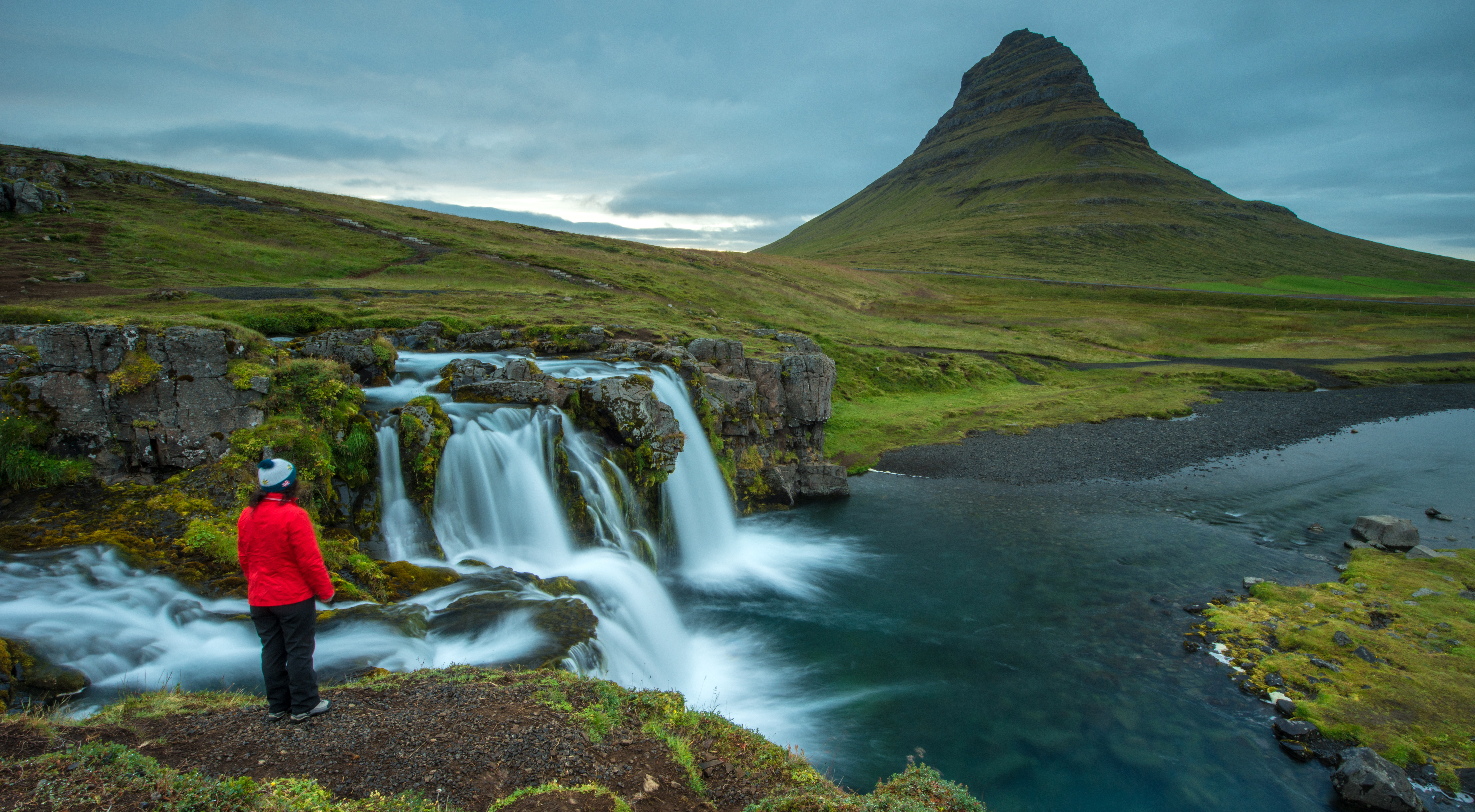 Woman with Red Jacket Looking at Kirkjufell Mountain