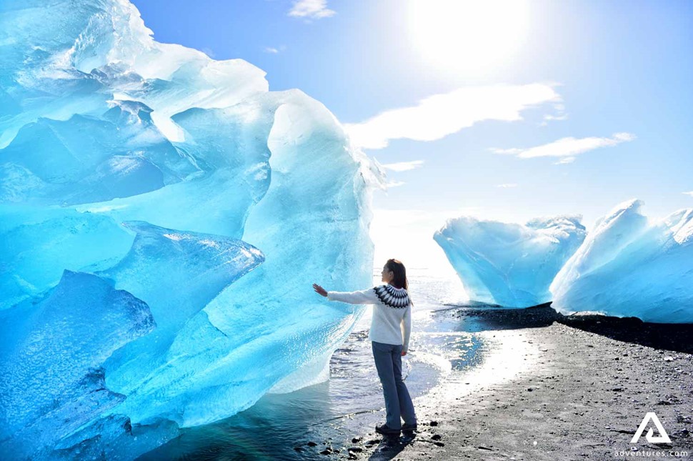 Woman Touching Huge Iceberg in Iceland