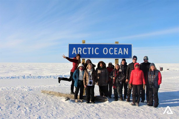 Group Posing by Arctic Ocean Sign