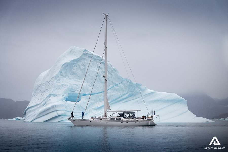 Sailing Boat Swims by Iceberg