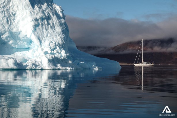 Sailing Boat near Giant Iceberg in Greenland