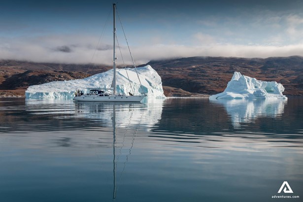 Yacht Swims by Icebergs near Shore in Greenland