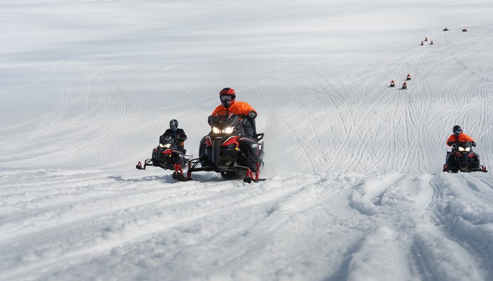 People Riding Snowmobiles On Glacier
