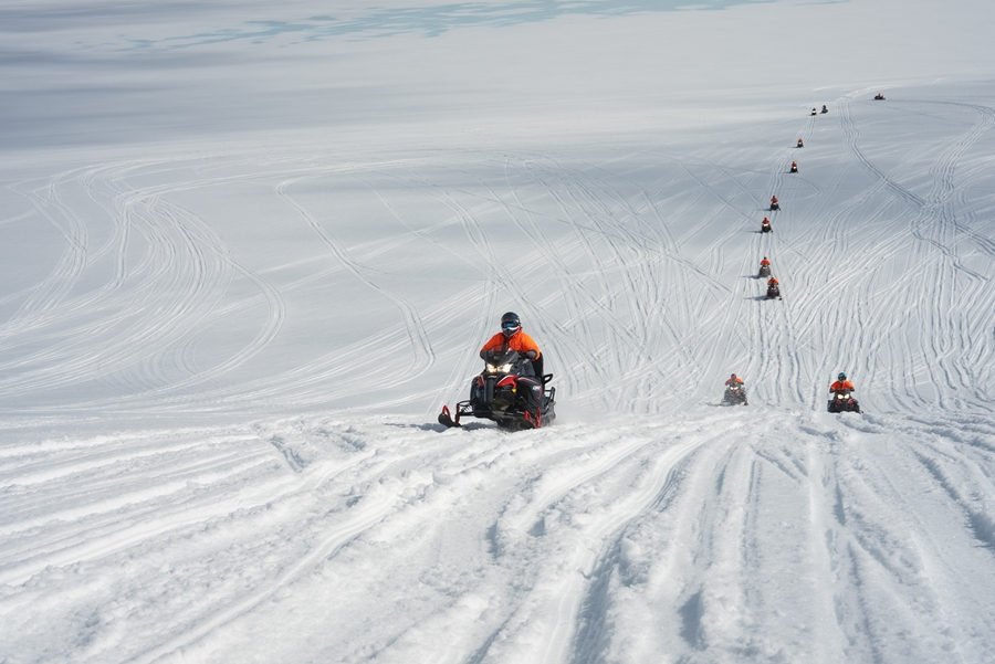 Group Driving Snowmobiles on Glacier