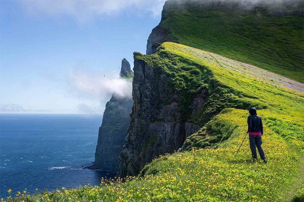 Woman Standing And Watching The Ocean From Cliffs Of Westman Islands