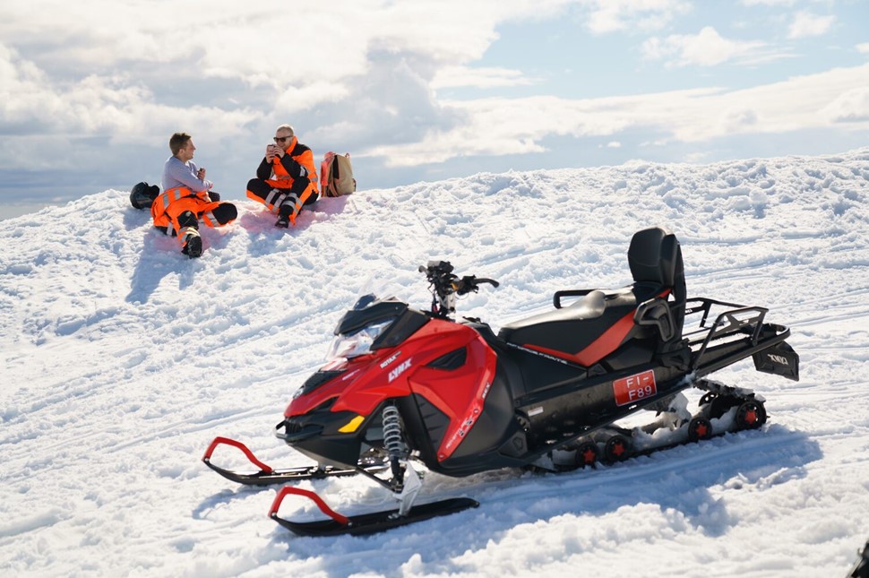 People taking a break in the middle of snowmobiling tour