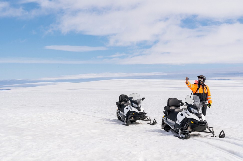 Person posing for a selfie next to snowmobile
