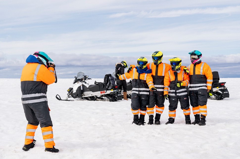 Person taking a group picture of snowmobile riders