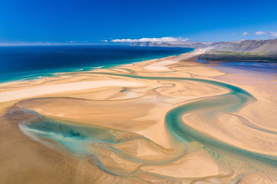 Bright Raudisandur sands and azure water streams from above