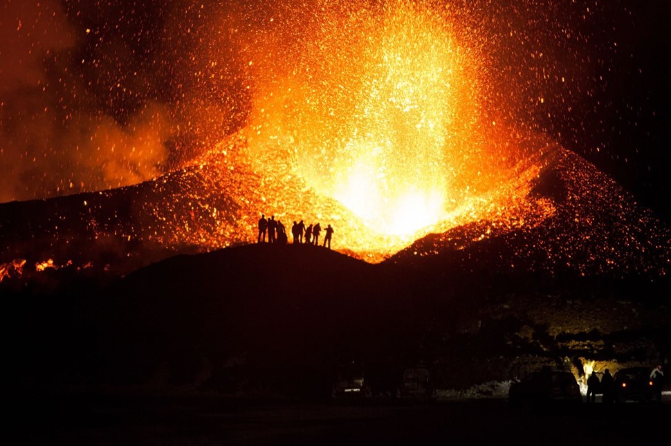 People standing in front of the volcanic eruption at Eyjafjallajökull in 2010
