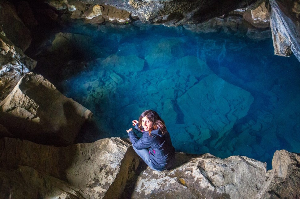 Tourist near blue water in Grjotagja cave 