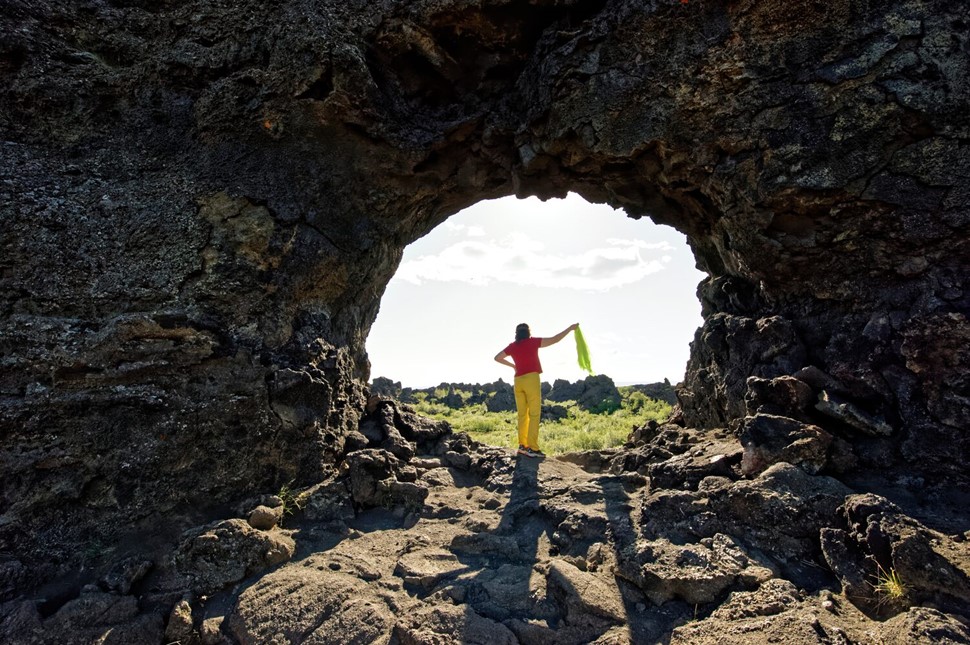 Woman posing under Dimmuborgir lava bridge