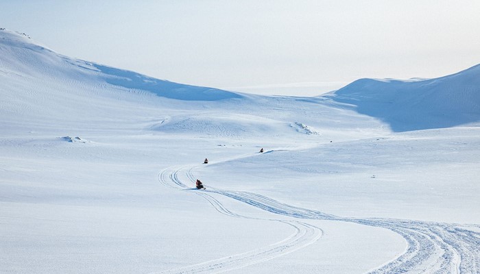 Couple snowmobiles riding on glacier
