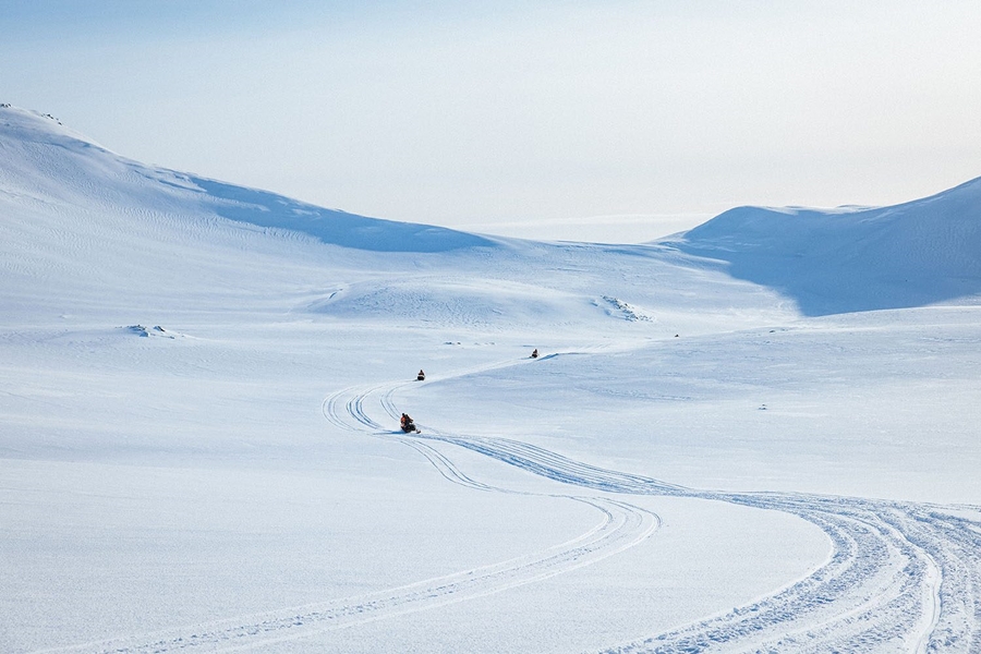 Couple snowmobiles riding on glacier