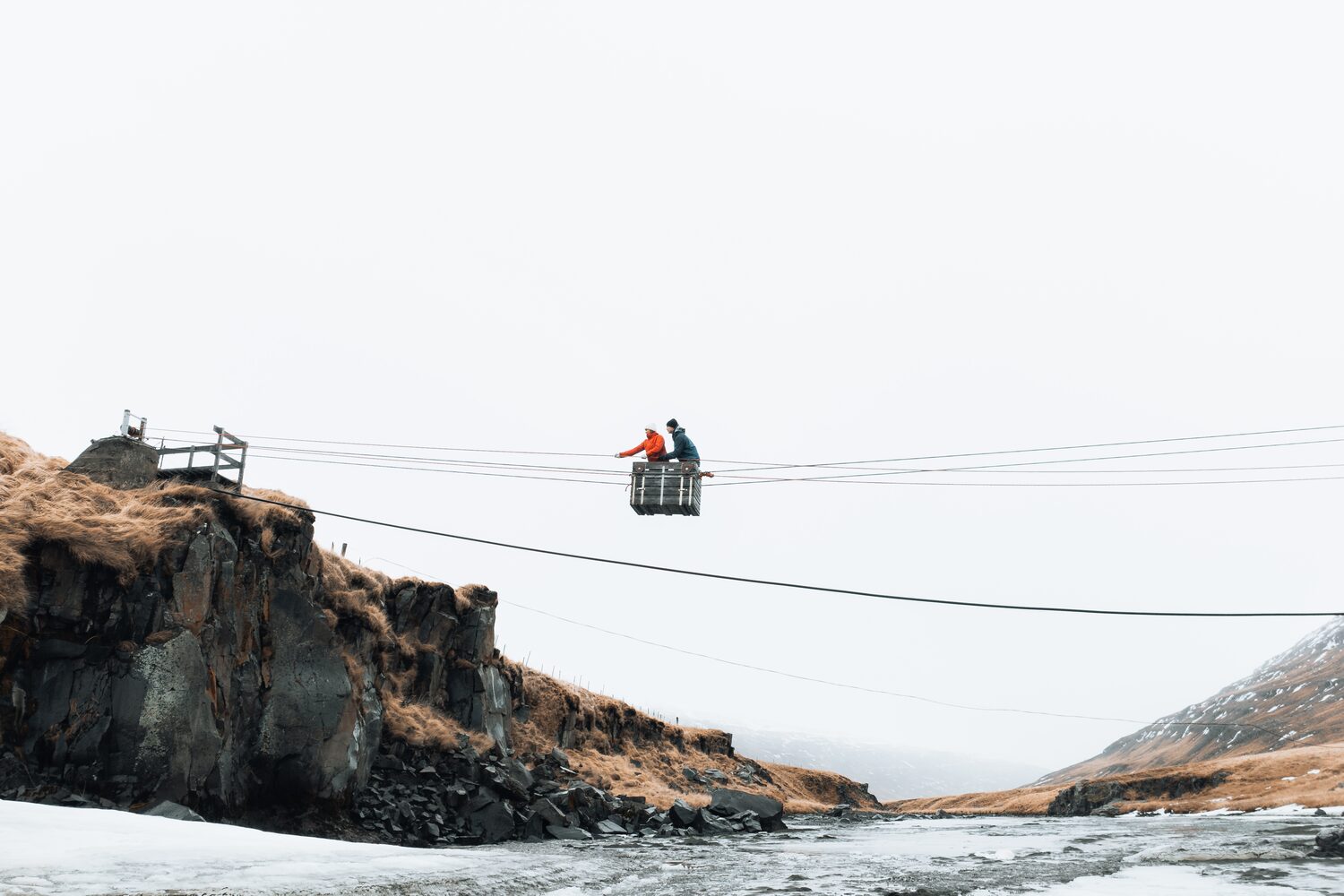 People crossing river with cable bridge
