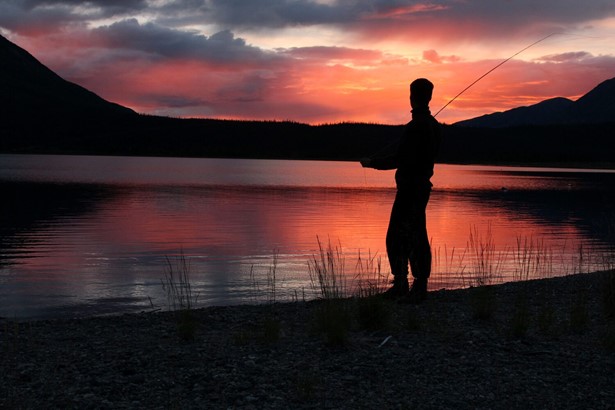 Man fishing at sunset with red sky