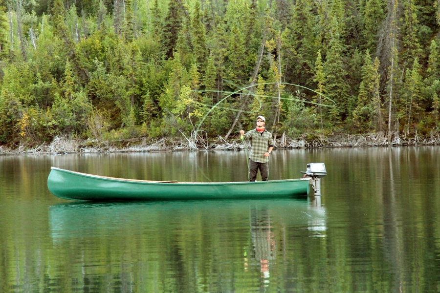 Man fishing in green boat on lake