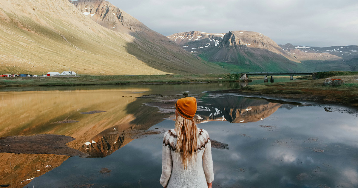 Woman autumn clothes looking over mountain landscape in Icelandic Fjords