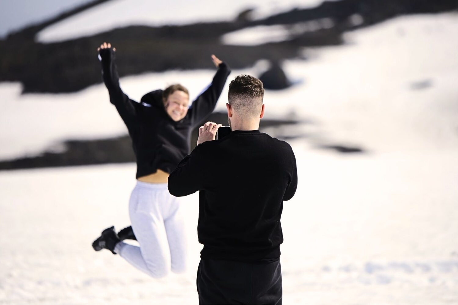 Man taking photo of woman posing on glacier
