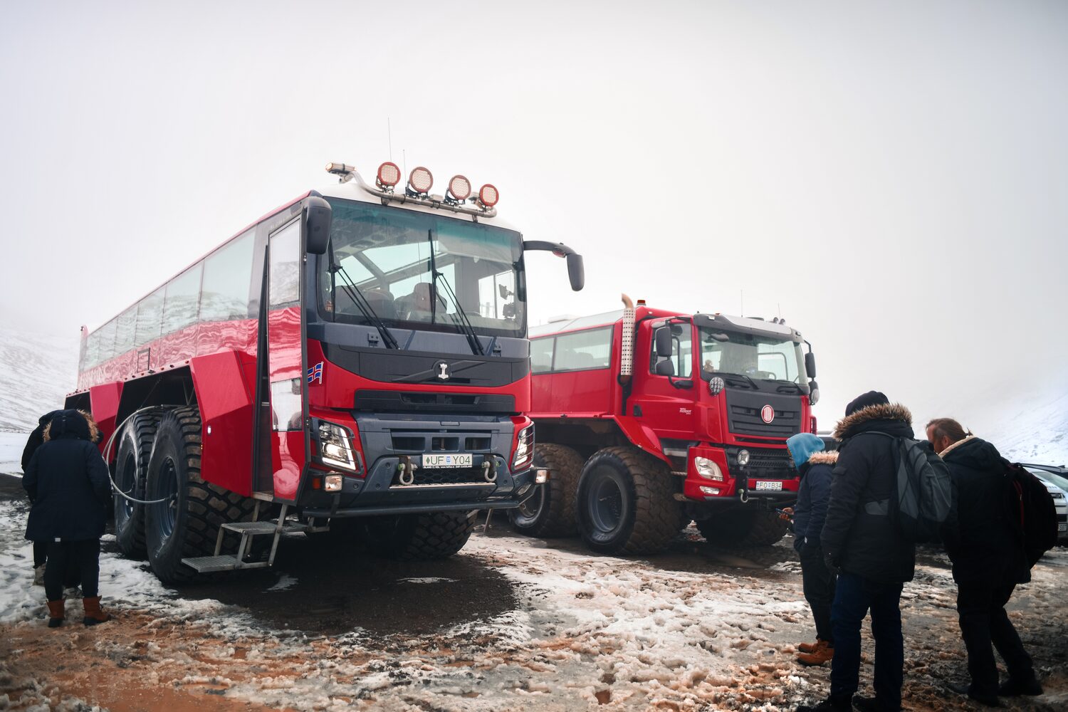 Two red giant trucks and people