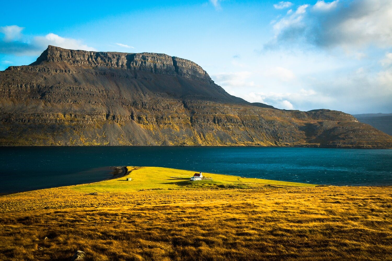 Westfjords Iceland House in the distance mountain surrounded by sea
