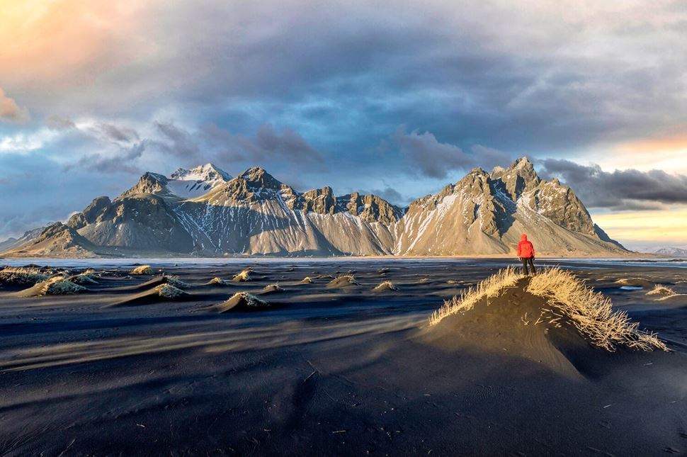 Hiker Vestrahorn Sand Beach Iceland Hiker watching colourful sunset over mountains at Vestrahorn black sand beach in Iceland