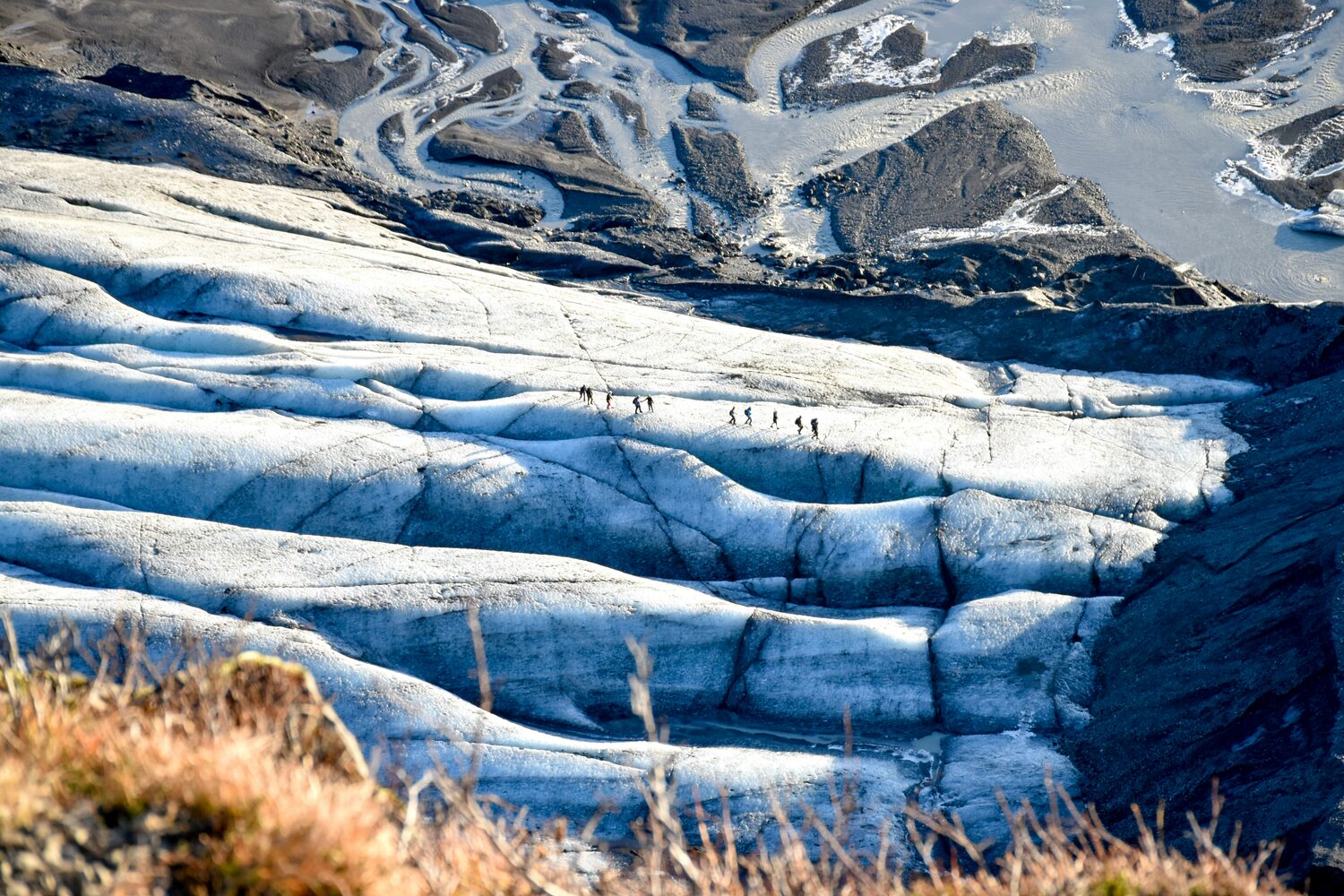 Aerial view of Sólheimajökull Glacier Hikers walking across glacier 