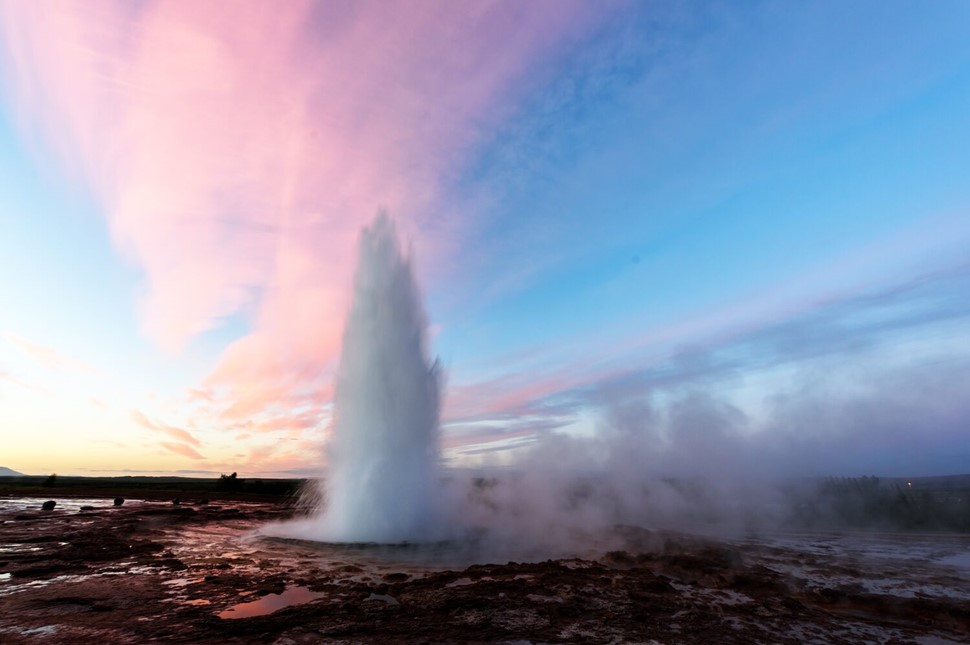 Strokkur geyser in Geysir area of Iceland with pink sunset skies 