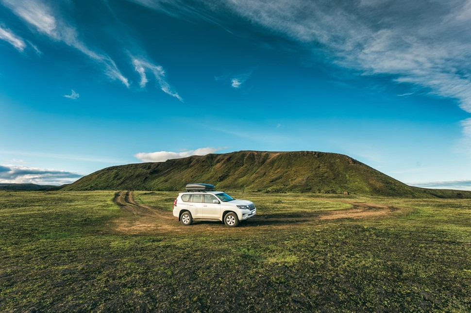 Outlander Jeep Parked on green Moss Lava fields of Iceland with blue skies