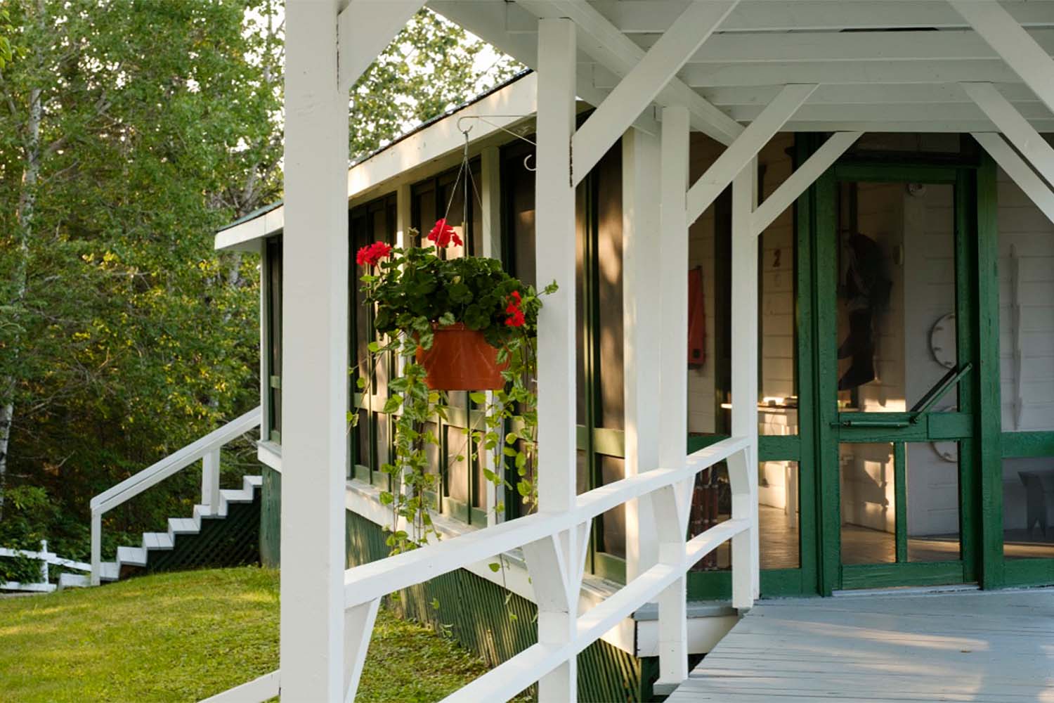 White and green wooden archway, with flowers hanging infront of fishing tour accommodation in Quebec Canada,