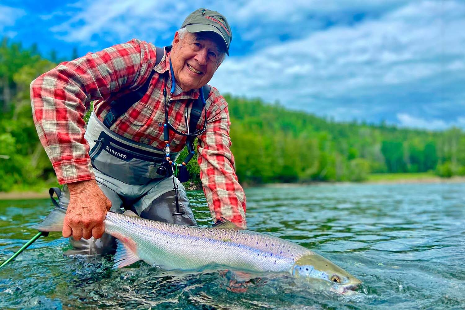 Man with red shirt holding fish in river