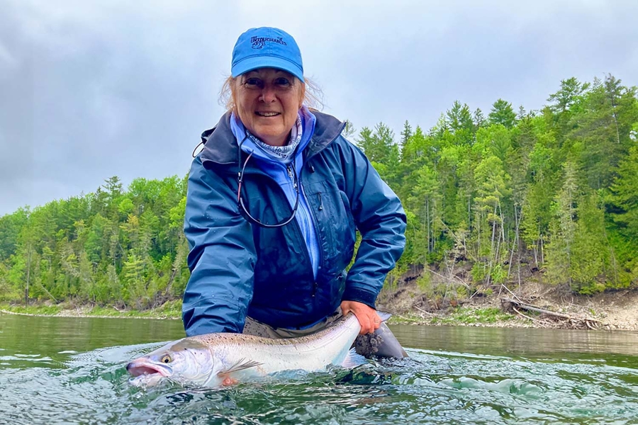 Woman with blue jacket and cap caught salmon in river