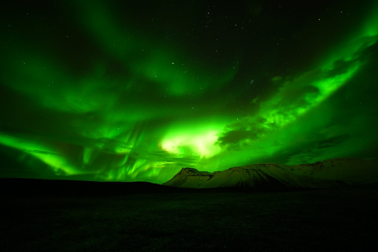 Northern Light above snowy mountain range at night