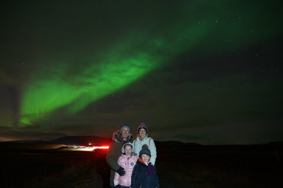 Mother, father and two children outside at night with Aurora in the sky