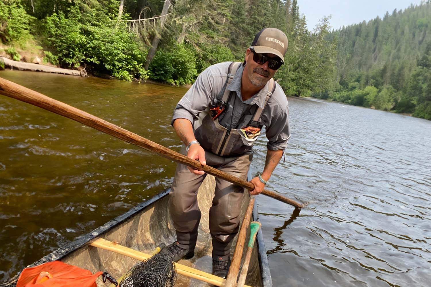 Fisherman swimming by boat in river