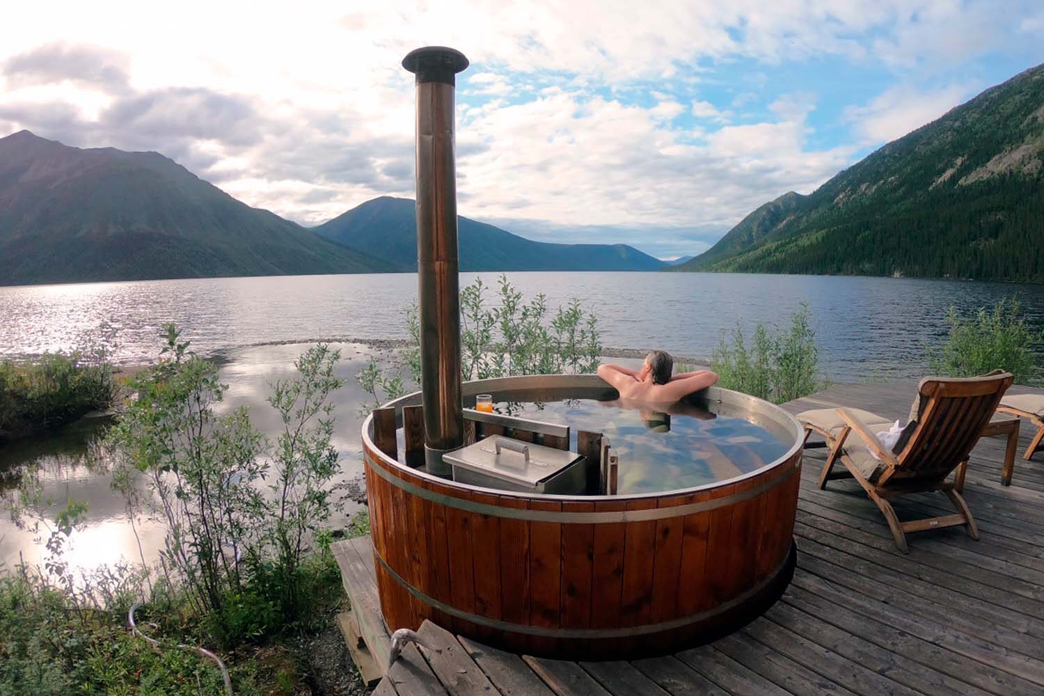 Woman enjoying hot tube by the lake in Yukon