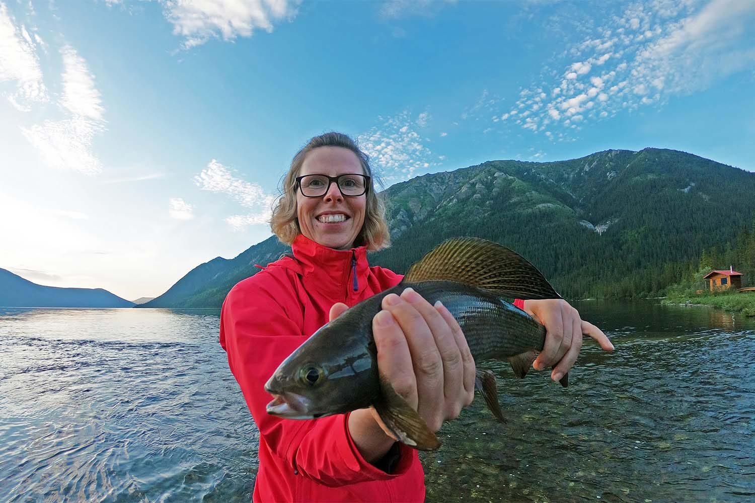 Happy woman with caught fish by lake
