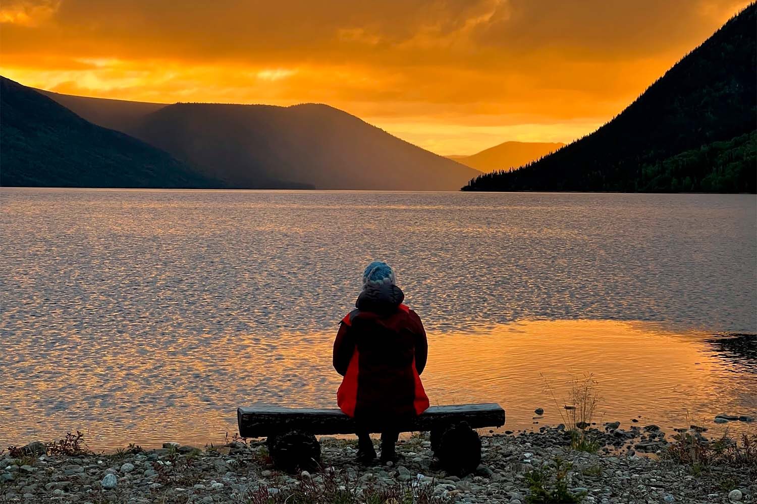 Woman sitting on bench by the Tincup lake at sunset