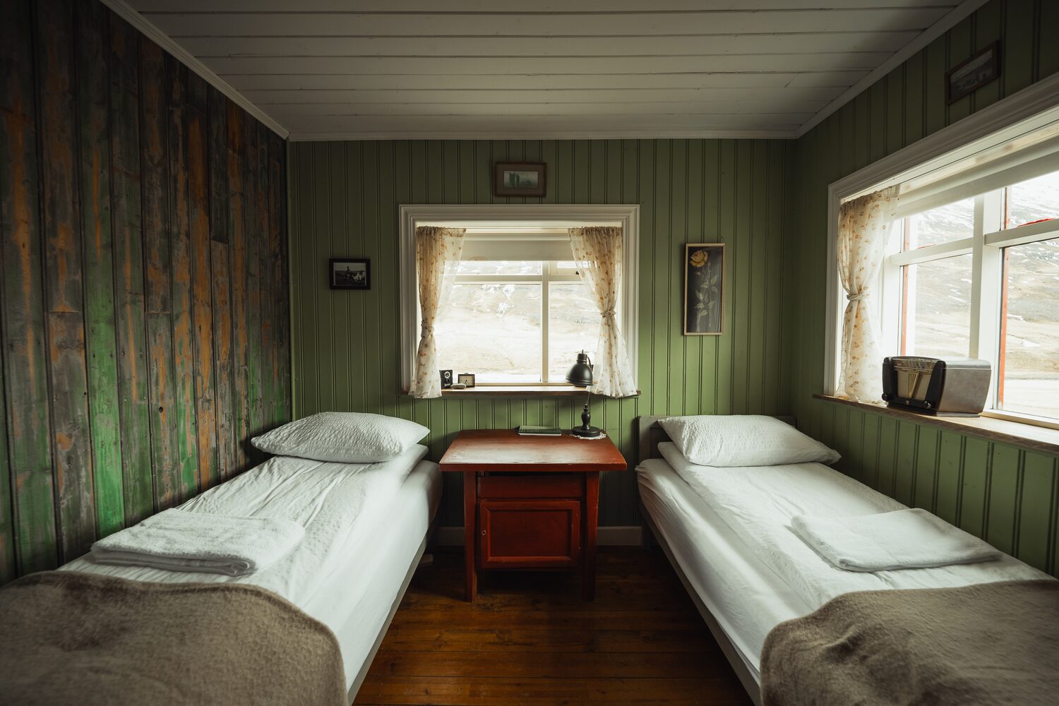 Two beds with cream colored sheets and green painted walls at wilderness center hotel room.