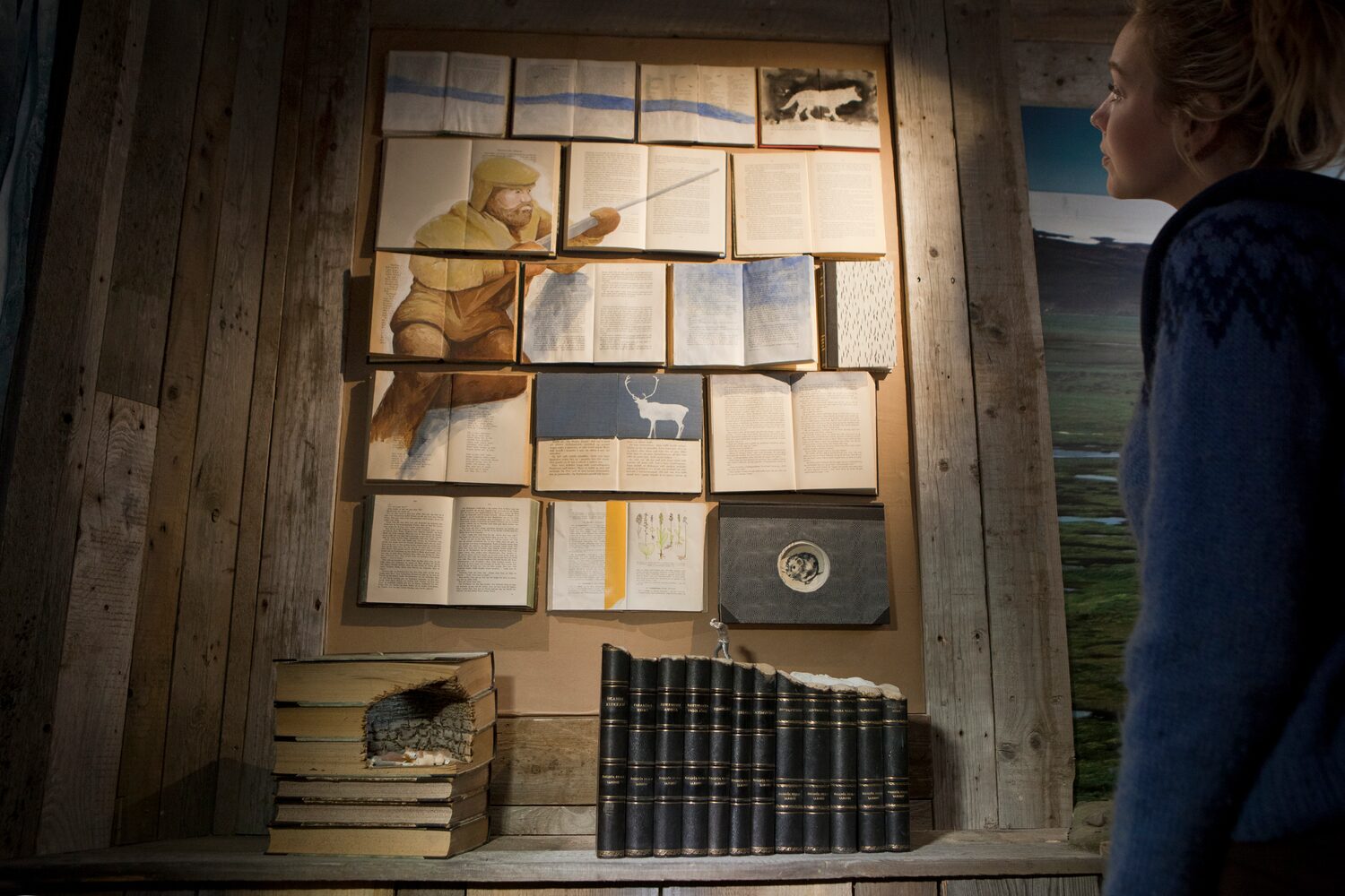Wall of artwork and books at wilderness center museum in Iceland.