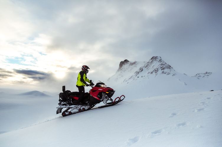 Uphill Snowmobile Person on snowmobile driving uphill in thick snow mountain landscape