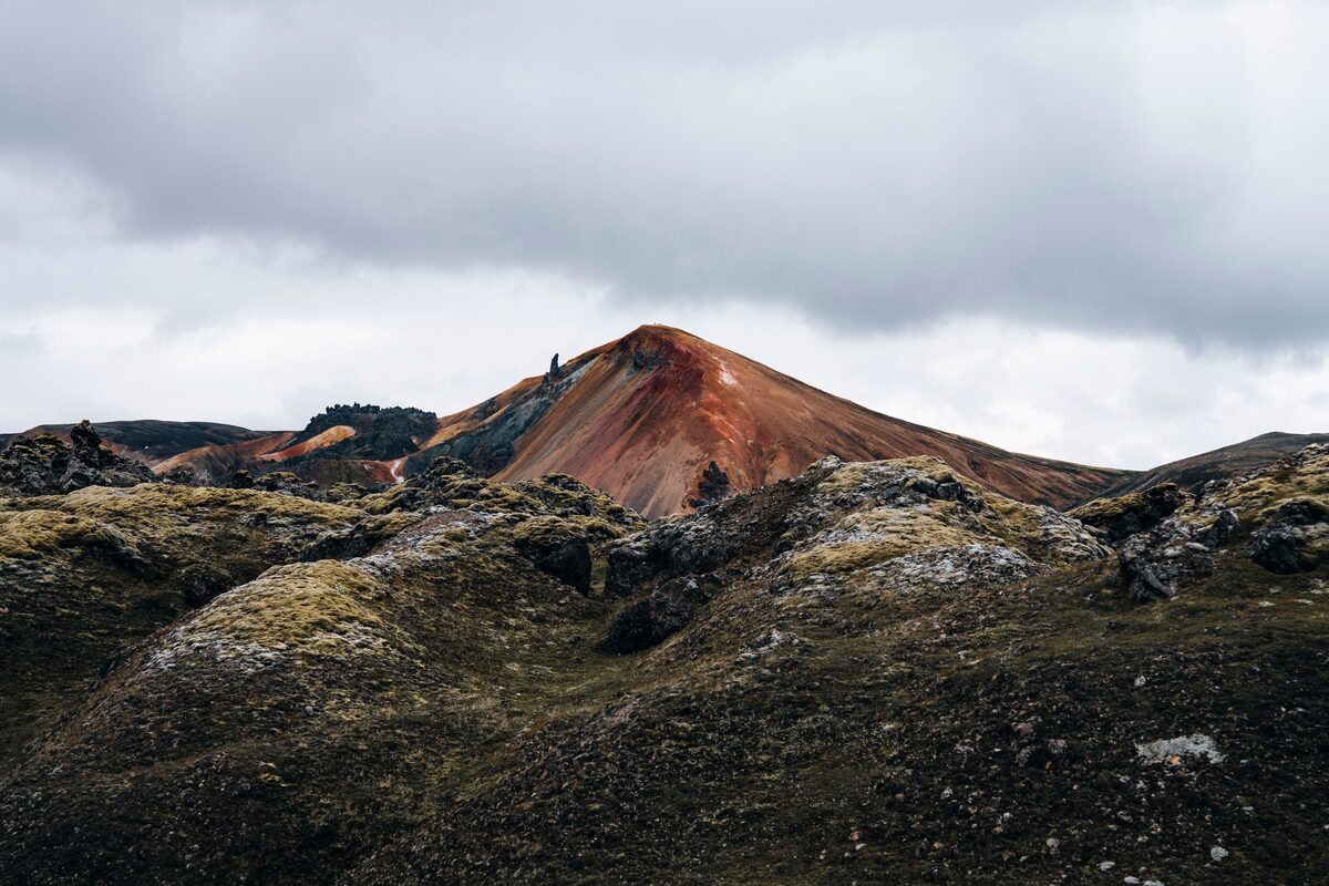 Rocky terrain in foreground with rhyolite multi colored mountain top in background