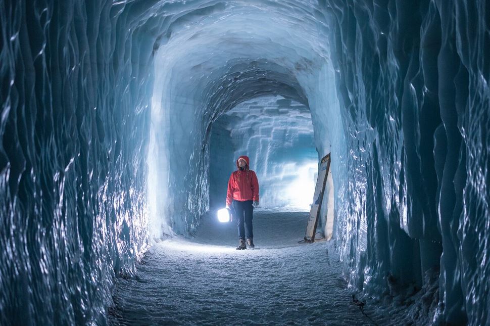 Woman walking in long ice tunnel under ground