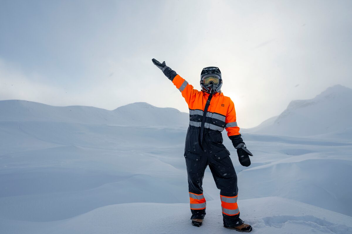 Man in orange snowmobiling gear standing posing for photo Langjokull glacier