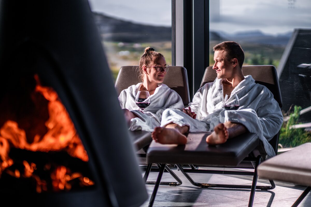 Young attractive happy couple relaxing in robes next to fireplace 